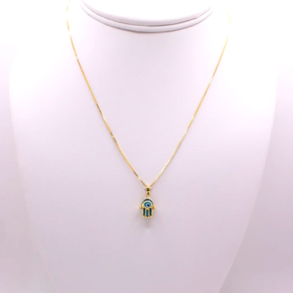 Hamsa pendant with a blue stone paired with a necklace.